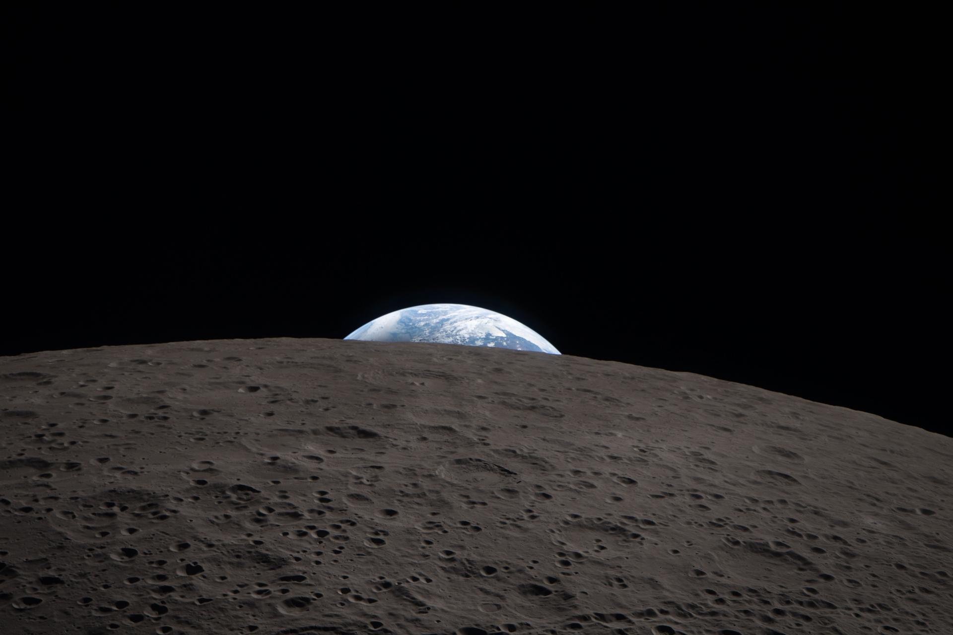 A Terra aparece acima do horizonte lunar, registrada durante a Artemis II.